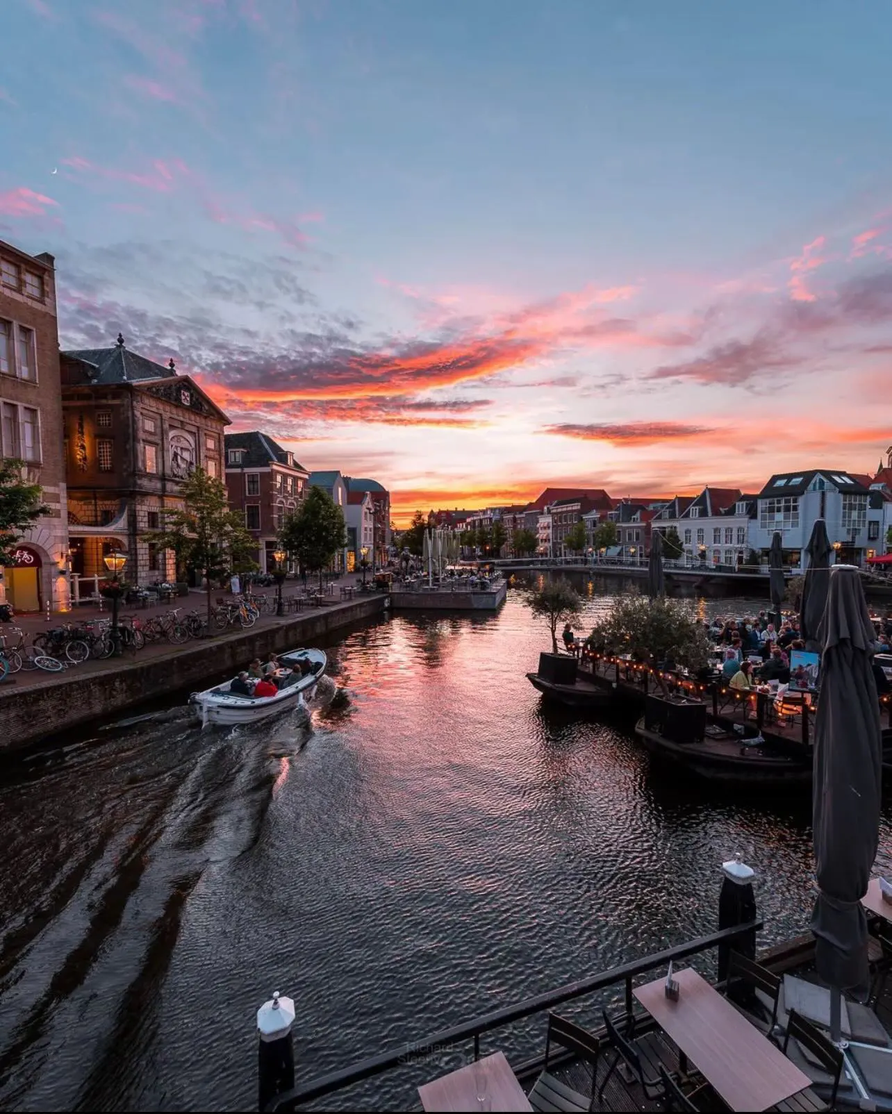 Boat on the Nieuwe Rijn in Leiden with waterside terraces at sunset Boat on the Nieuwe Rijn in Leiden with waterside terraces at sunset